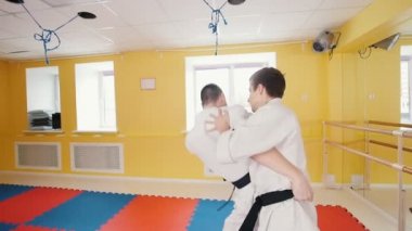 Atletik erkekler aikido dövüş sanatı meşgul. Bir adam rakibini yakalar ve onu üzerine atar