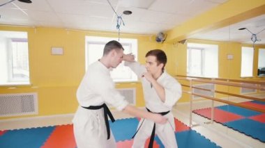 Atletik erkekler Aikido becerilerini eğitti. Bir adam rakibini yakalar ve onu üzerine atar