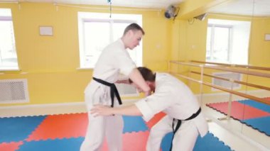 Atletik erkekler stüdyoda Aikido becerilerini eğitim. Koruma tekniği gösteriliyor