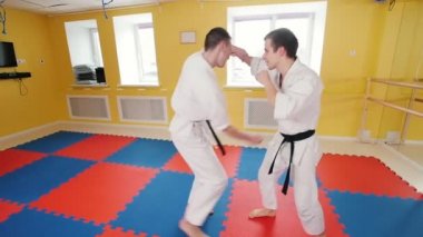 Stüdyodan Aikido becerilerini eğiten iki adam. Bir adam rakibini yakalayıp yere atar.