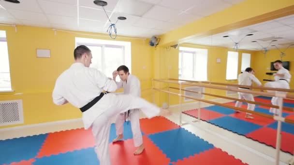 Dua pria atletik melatih keterampilan aikido mereka di studio. Melindungi dari pukulan kaki dan melemparkan lawan di lantai — Stok Video