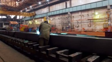 İnşaat fabrikası. Vinç büyük bir bölümünde bir kaynak makinesi kullanarak bir kask bir adam