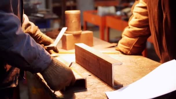 Construcción de plantas. Un hombre trabajando con un pequeño detalle de hierro — Vídeos de Stock