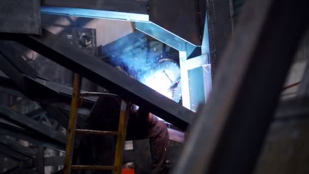 Een man zit op zijn werkplek en met behulp van een lastoestel. Helder blauwe verlichting — Stockvideo