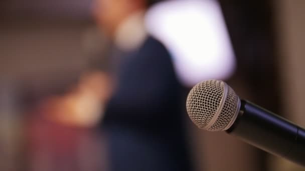 Una conferenza di lavoro nella hall. Un uomo che parla sul palco. Un microfono in primo piano — Video Stock