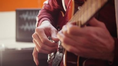 Bir müzisyen adam stüdyoda gitar oynuyor ve ses kaydı