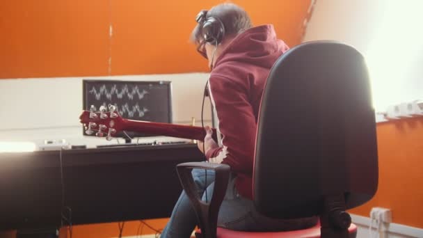 스튜디오에서 컴퓨터에 앉아 노래를 녹음 하는 헤드폰의 음악가 남자 — 비디오