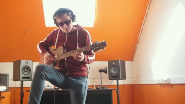 Un hombre con auriculares tocando la guitarra en un estudio de grabación de sonido — Vídeos de Stock