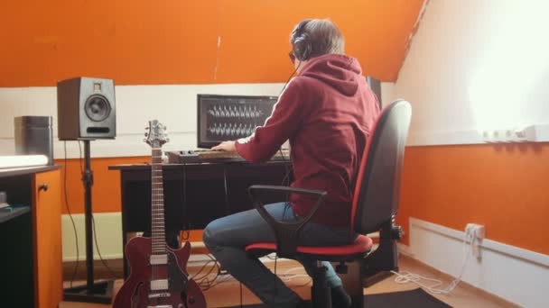 Ένας άντρας με ακουστικά που παίζει κιθάρα σε στούντιο ηχογράφησης. — Αρχείο Βίντεο