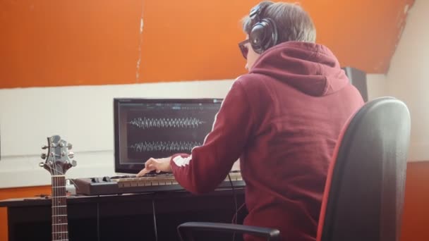 Музикант працює в звуковій студії. Одягаючи навушники і починаючи відтворювати Midi-клавіатуру — стокове відео