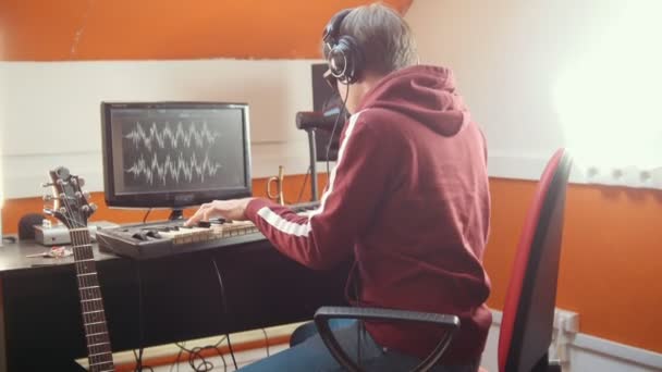 Een muzikant man spelen op een MIDI-toetsenbord en opnemen voor een track — Stockvideo