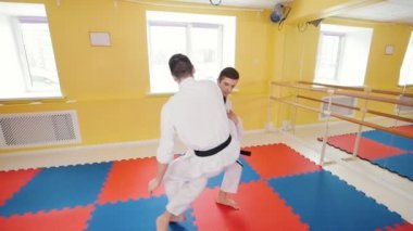 Dövüş sanatları. İki atletik adam stüdyosunda Aikido becerilerini eğitti. Bir bacak vurmak ve yere rakibin atma koruma