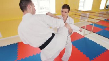 Dövüş sanatları. İki atletik erkek Aikido becerilerini eğitti. Bir bacak vurmak ve yere rakibin atma koruma