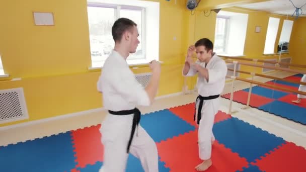 Artes marciales. Dos hombres entrenando sus habilidades de aikido en el estudio. Protegiendo de un golpe en la pierna y tirando al oponente al suelo — Vídeos de Stock