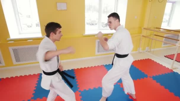 Artes marciales. Dos hombres atléticos entrenando sus habilidades aikido en el estudio. Tirando al oponente al suelo y produciendo estrangulamiento — Vídeo de stock