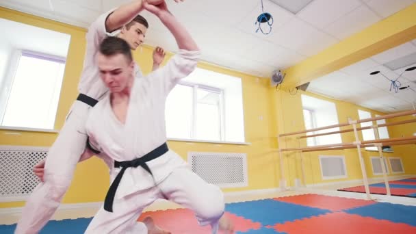 Két sportos férfi képzés az aikido képességeit a stúdióban. Semlegesítő az ellenfél, és dobott neki a padlón — Stock videók