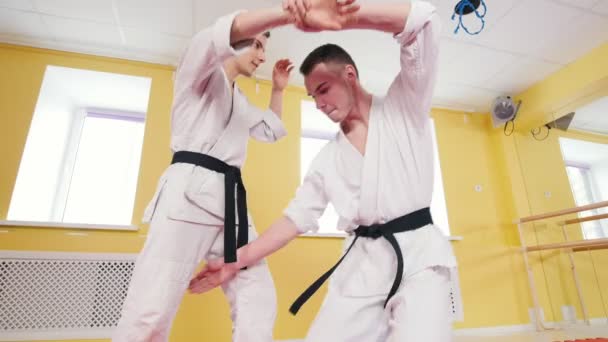 Kampsport. To atletiske menn trener aikido-ferdigheter i studioet. Nøytraliserer motstanderen og kaster ham på gulvet – stockvideo