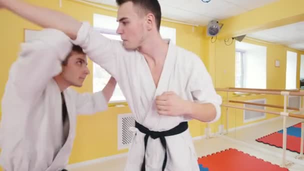 Twee atletische mannen trainen hun Aikido vaardigheden. Parries de hit en het gooien van de tegenstander op de vloer — Stockvideo
