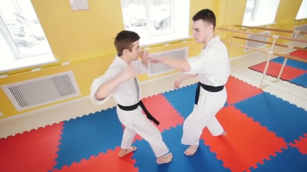 Vechtsporten. Twee atletische mannen trainen hun Aikido vaardigheden. Parries de hit en het gooien van de tegenstander op de vloer — Stockvideo