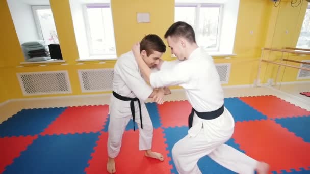 Kampfkunst. Zwei sportliche Männer trainieren ihre Aikido-Fähigkeiten. Schlag mit dem Knie auf den Gegner — Stockvideo