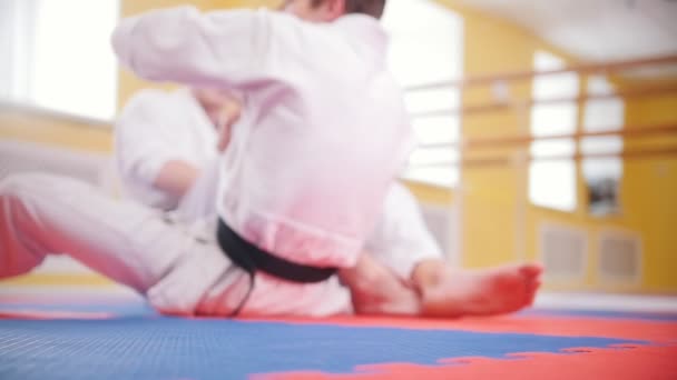 Artes marciales. Dos hombres atléticos entrenando sus habilidades aikido en el estudio. Acostado en el suelo — Vídeos de Stock