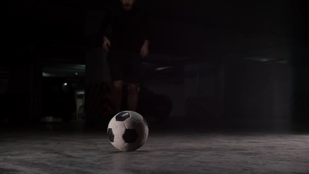 Tiefgarage. Ein Fußballmann rennt aus der Dunkelheit und tritt gegen den Ball — Stockvideo