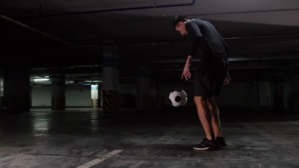 Estacionamento subterrâneo. Um jovem homem de futebol treinando suas habilidades de futebol — Vídeo de Stock