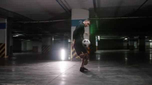 Underjordisk parkering. En ung fotbolls man tränar sin fotboll färdigheter med bollen — Stockvideo