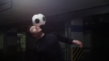 Top ile genç bir futbol adamı eğitim hileler. Kafa ve omuzları ile topu dengelemek ve vurmak