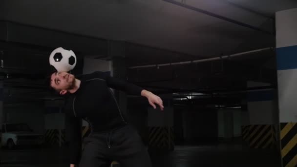 Ένας νέος ποδοσφαιρικός άνθρωπος προπόνηση κόλπα με την μπάλα στο υπόγειο πάρκινγκ — Αρχείο Βίντεο
