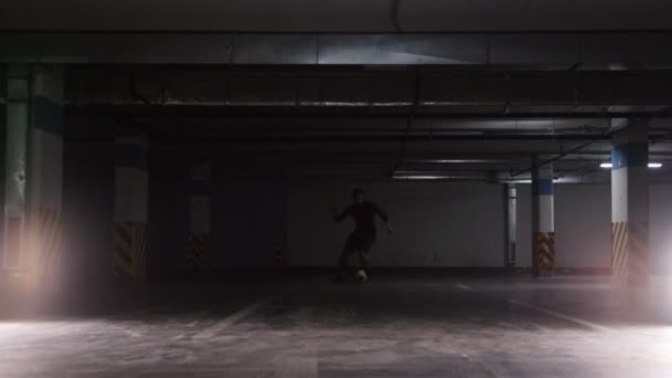 Un footballeur menant le ballon en utilisant des feintes sur le parking souterrain 