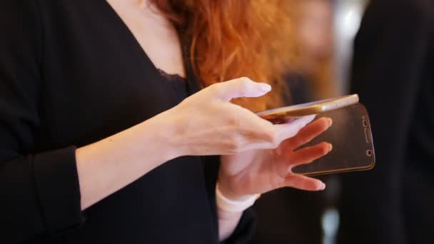 A business conference in the hall. A woman searching for something in her phone — Stock Video