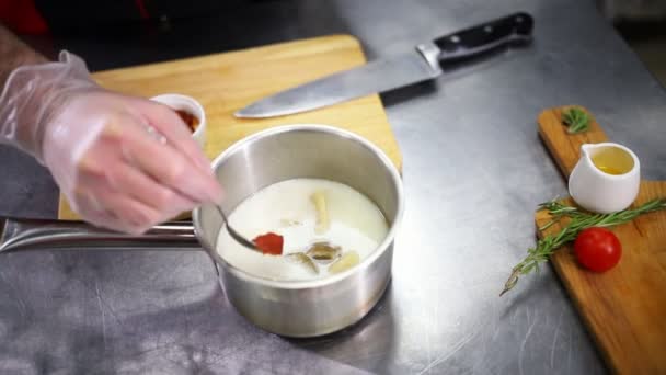 Šéfkuchař pracující v kuchyni. Přidání omáčky do polévky — Stock video