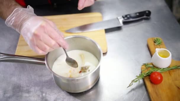 Een chef-kok die in de keuken werkt. Het toevoegen van een saus in de soep en het mengen van het — Stockvideo