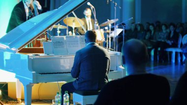 Konserde piyano çalan bir adam ve audince onu izliyor.