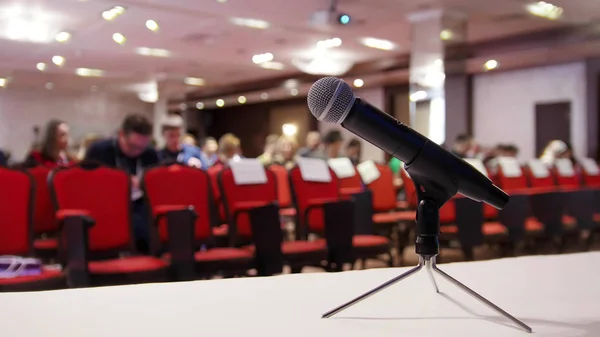 A business conference in the hall. People sitting on the chairs. A microphone on a foreground — Stock Photo, Image