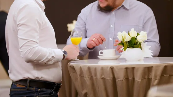 Una conferencia de negocios. Gente de pie sobre la mesa. Un hombre sosteniendo el vaso de jugo — Foto de Stock