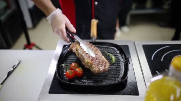 Een chef-kok die in de keuken werkt. Het maken van een gebraden biefstuk in de pan — Stockvideo