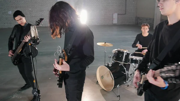 Un jeune groupe de rock qui fait une répétition dans un garage. Membres d'un groupe portant des vêtements noirs — Photo