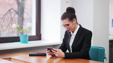 İş konsepti. Kulaklıkta bir kadın telefonuna bakıyor