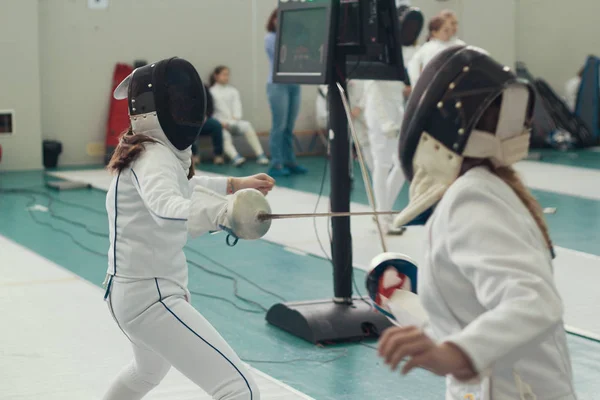 Dos jóvenes esgrimistas teniendo duelo de esgrima en el torneo — Foto de Stock