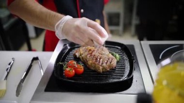 Mutfakta çalışan bir şef. Tava bir biftek kızartma ve üzerinde fırça