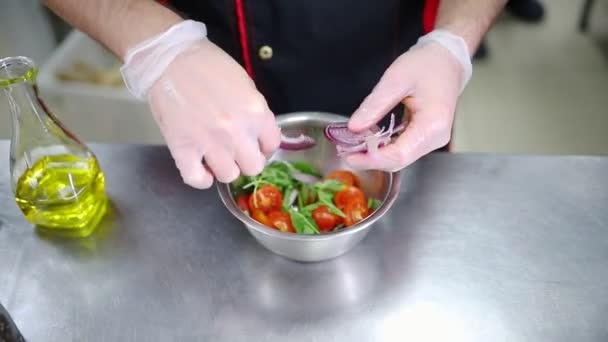 Um chef a trabalhar na cozinha. A fazer uma salada. Adicione a cebola — Vídeo de Stock