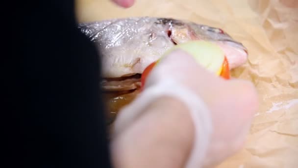 En som arbetar i köket. Fyllning av fisk med lök och tomat — Stockvideo