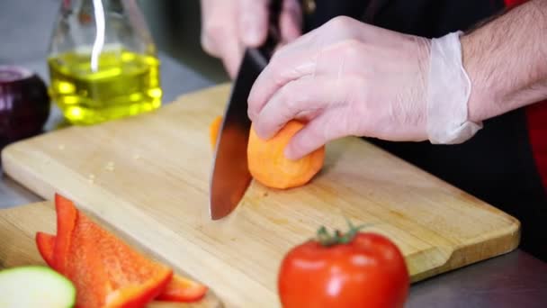 Een chef-kok die in de keuken werkt. Snijden van de wortel — Stockvideo