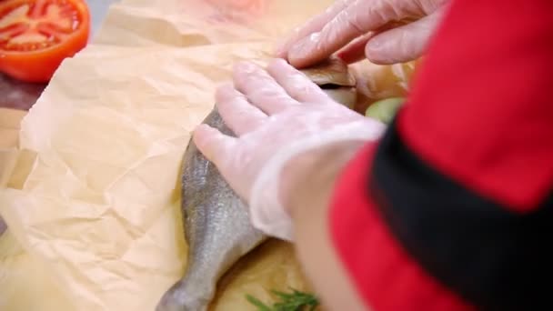 Um chef a trabalhar na cozinha. Enchendo o peixe com legumes e untando o peixe com um óleo — Vídeo de Stock