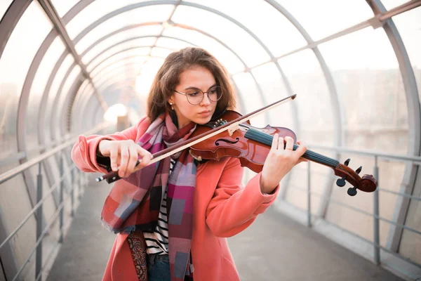 Молодая женщина в очках играет на скрипке в верхнем проходе — стоковое фото