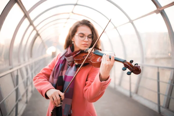 Mujer joven inspirada en gafas tocando un violín en el pasaje de arriba —  Fotos de Stock