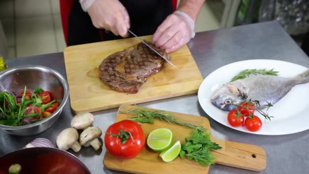 A konyhában dolgozó séf. Egy férfi vágás a steak — Stock videók