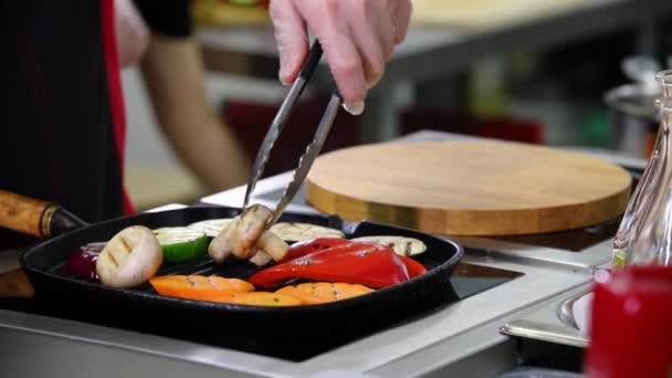 Un chef trabajando en la cocina. Un hombre calentando las setas y verduras en la sartén — Vídeos de Stock